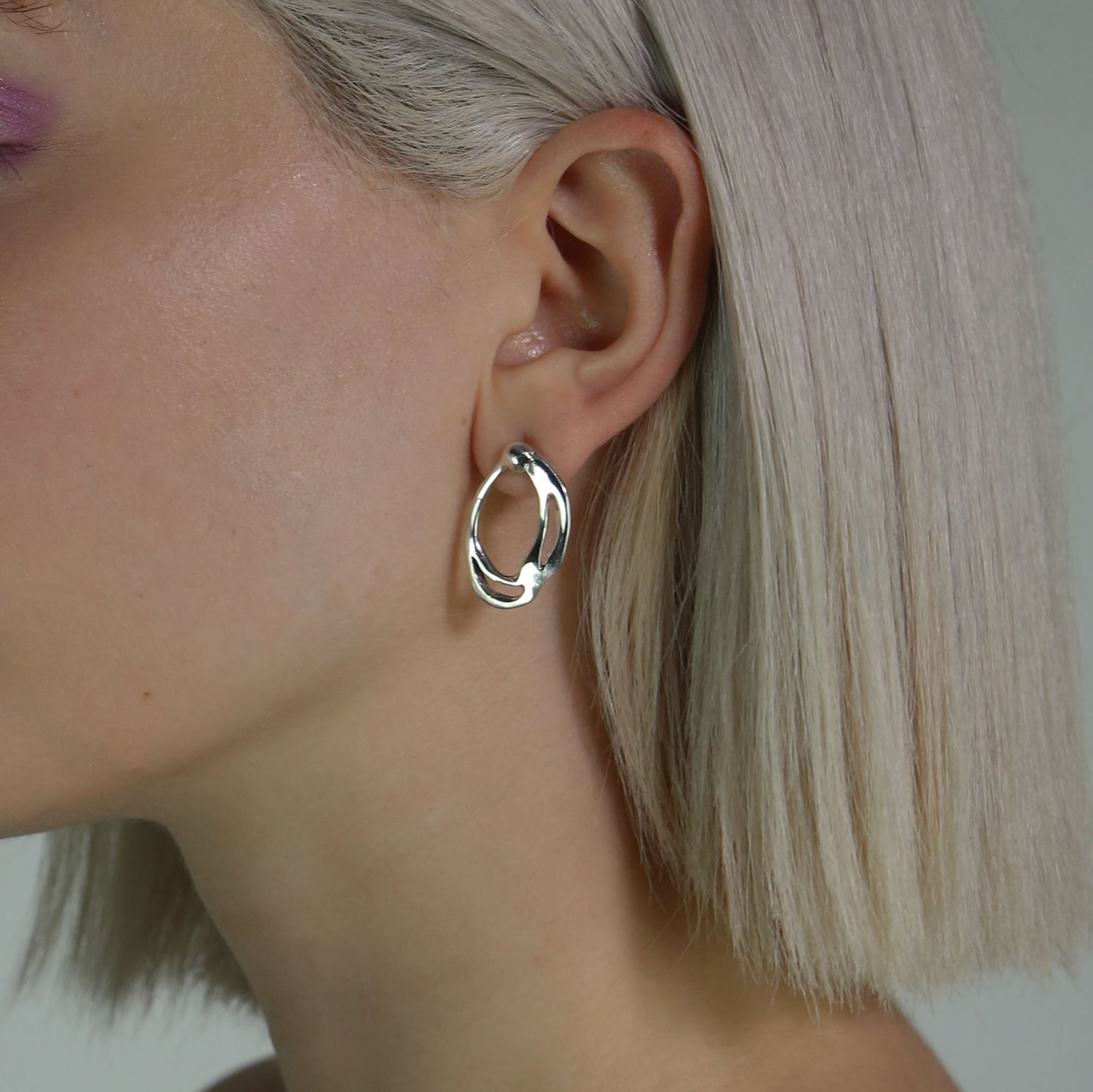 Leim earrings are handmade from 925 sterling silver. Their shape is oval with various cuts on the inside, and they are polished and shiny