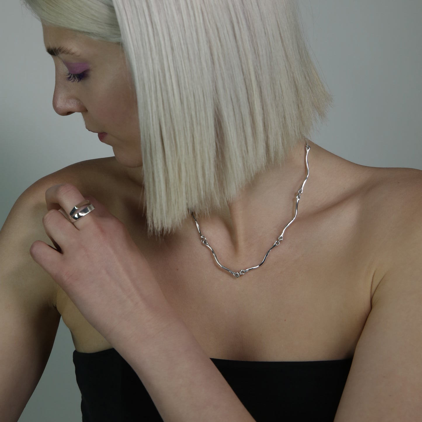 The Rogrande necklace is handmade and made of 925 sterling silver. It features small delicate wavy elements connected by rings, creating a smooth and shiny surface