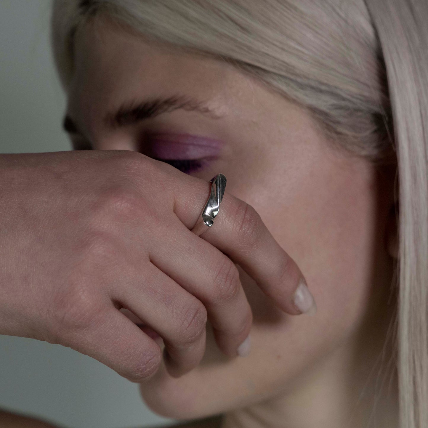 The Shai ring is a handmade piece crafted from 925 sterling silver. It is delicate and has a square shape with different lines on its surface. It has a shiny finish