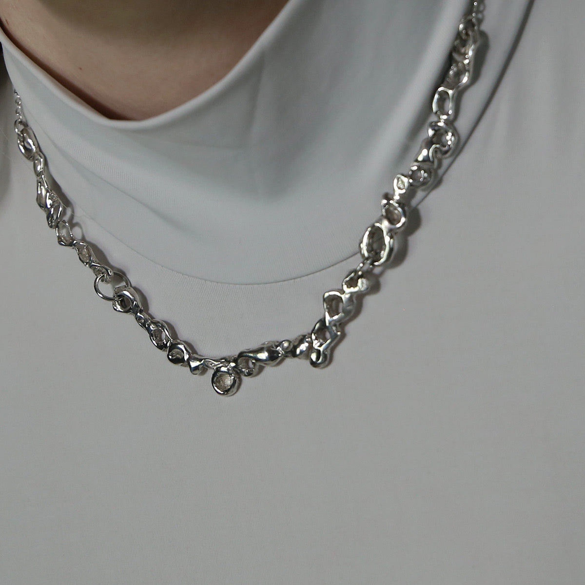 The handmade necklace is made of 925 sterling silver. It features a carved design, and at the end, there is a chain. The surface is polished, giving it a glossy finish