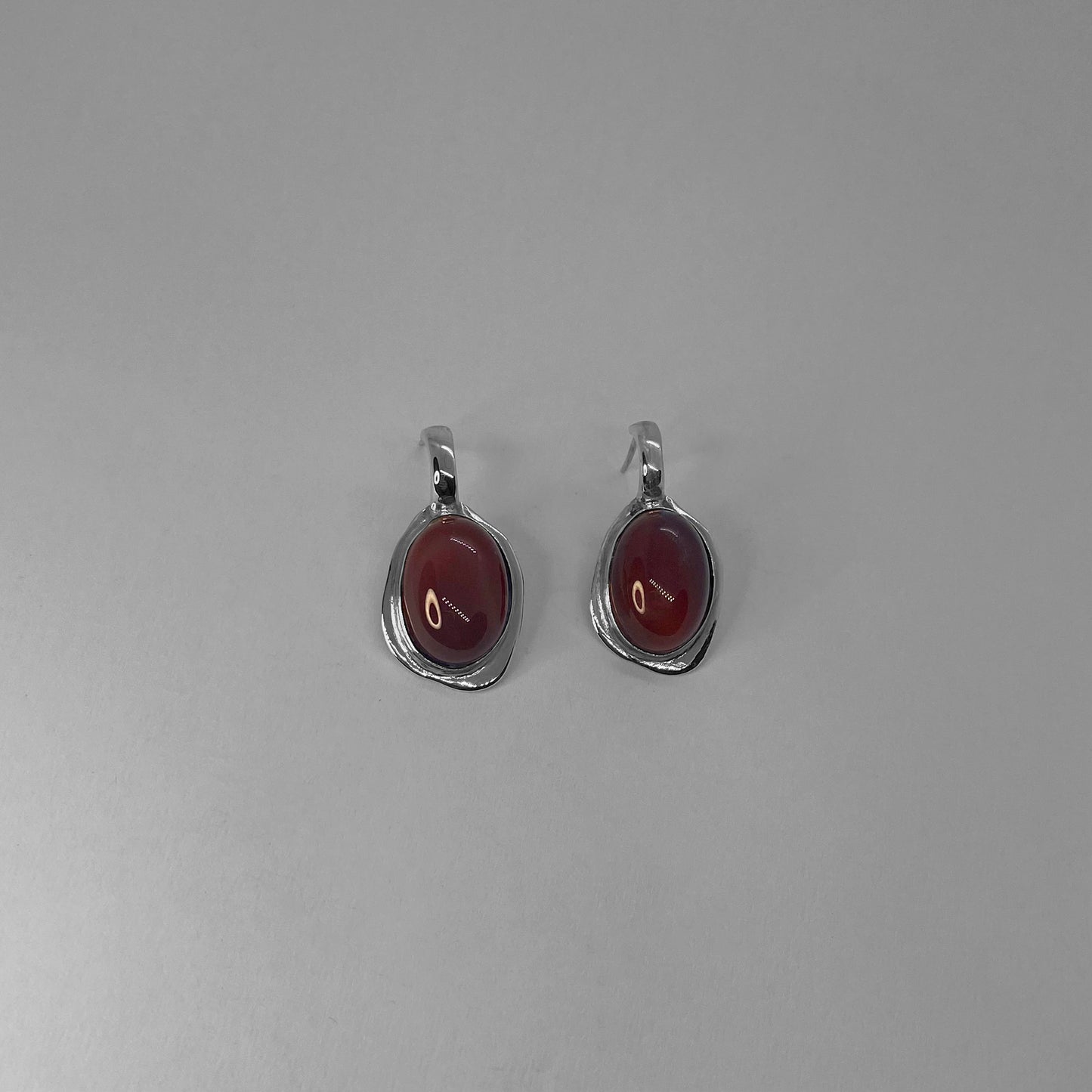 Galene earrings are handmade and made of 925 silver. They are smooth and shiny. The stone featured in the earrings is a semi-precious gemstone. There are two color options: red (carnelian) and black (agate).