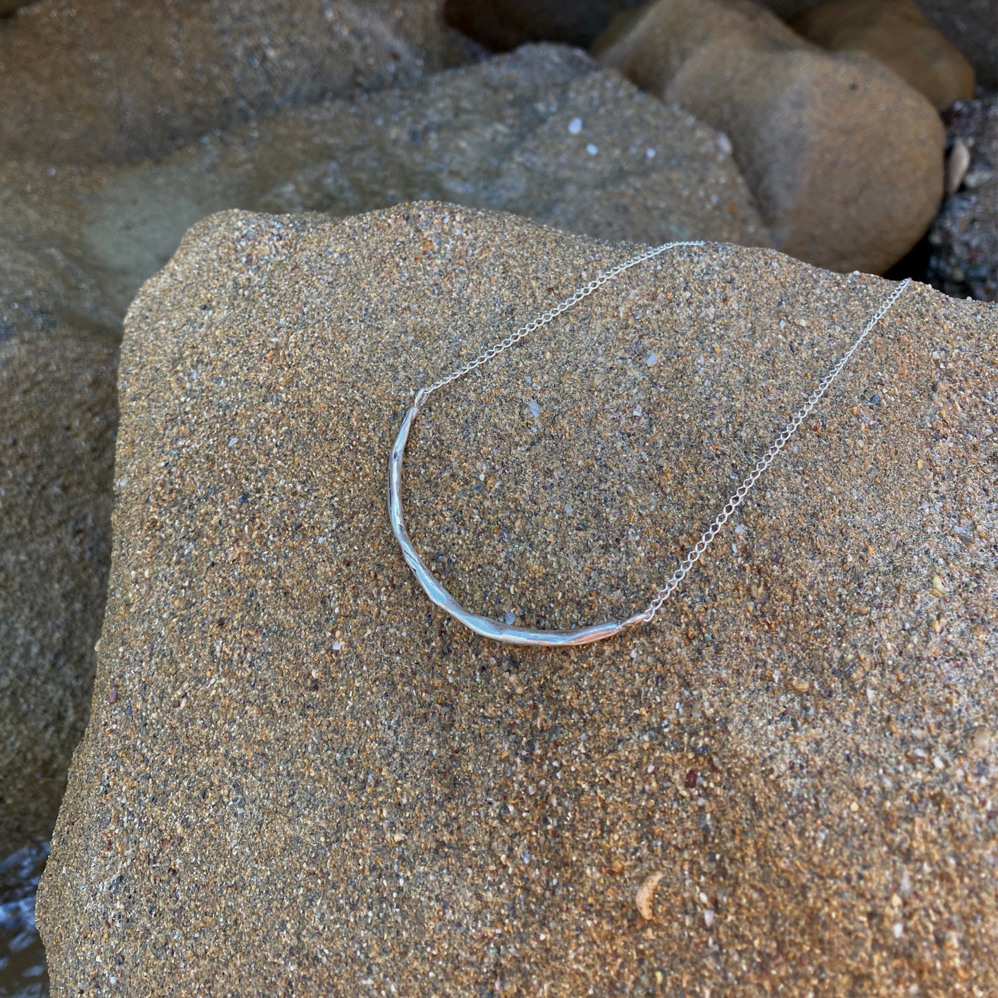 The Briliante necklace is a handmade piece crafted from sterling silver 925. It features a minimal silver strip with a textured appearance, providing a glossy finish while gracefully embracing the neck.
