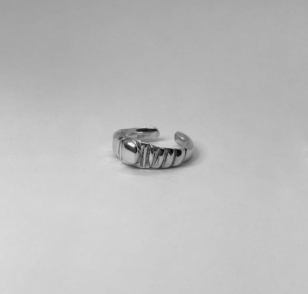 The Arctium ring is a handmade piece made of 925 sterling silver. It features thin lines on its surface and a thick silver circle at its center. It has a glossy finish