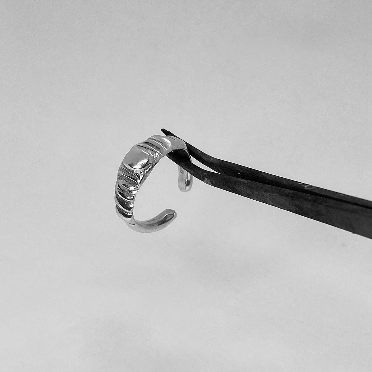 The Arctium ring is a handmade piece made of 925 sterling silver. It features thin lines on its surface and a thick silver circle at its center. It has a glossy finish