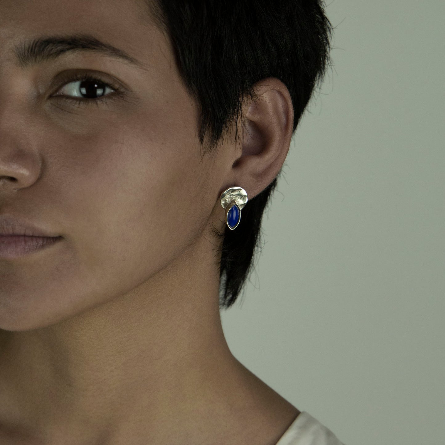 The Shai ring is a handmade piece crafted from 925 sterling silver. It is delicate and has a square shape with different lines on its surface. It has a shiny finish