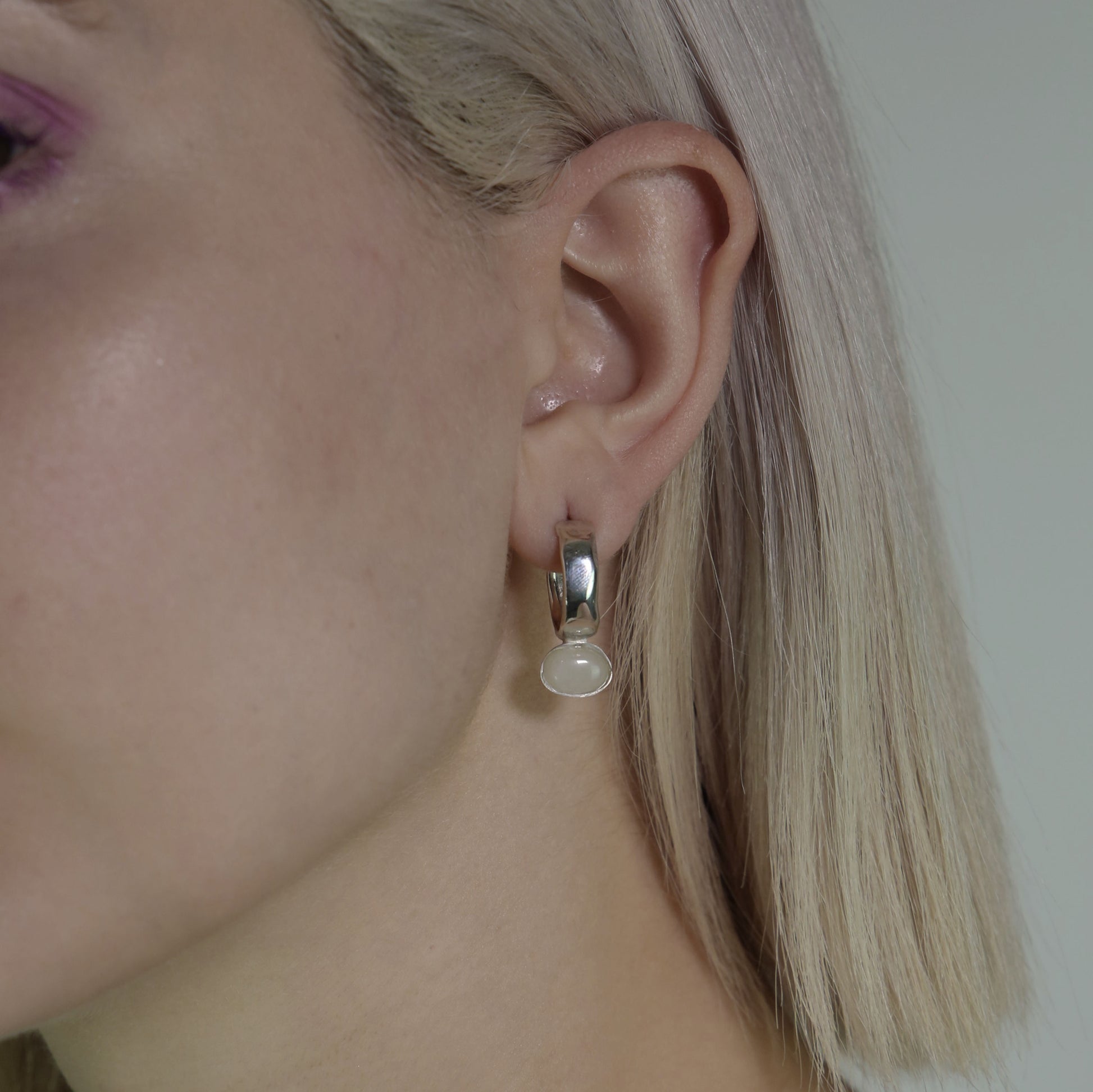 The small circle earrings are handmade and crafted from silver 925. The accompanying stone is semiprecious and is called white Haolite. The earrings are smooth and glossy.