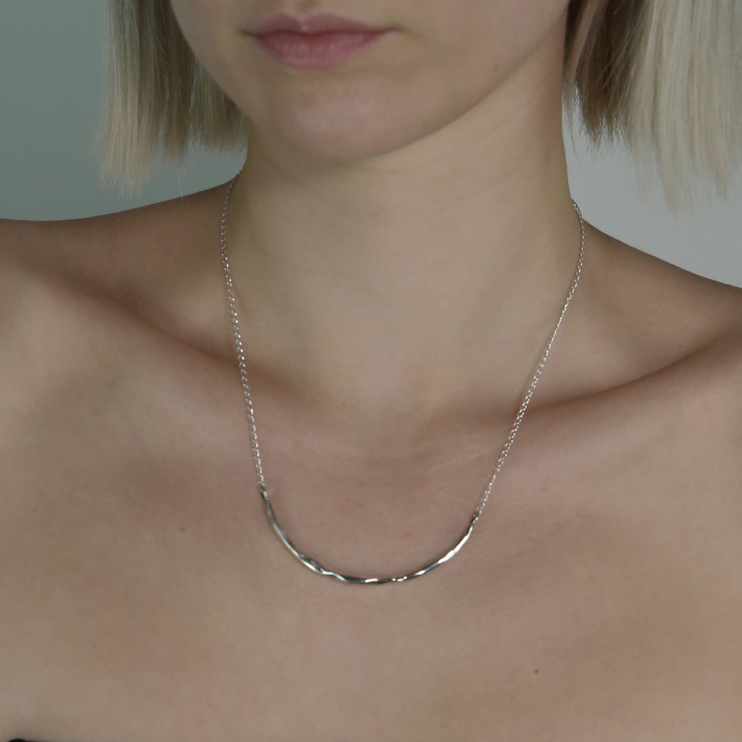 The Briliante necklace is a handmade piece crafted from sterling silver 925. It features a minimal silver strip with a textured appearance, providing a glossy finish while gracefully embracing the neck. 