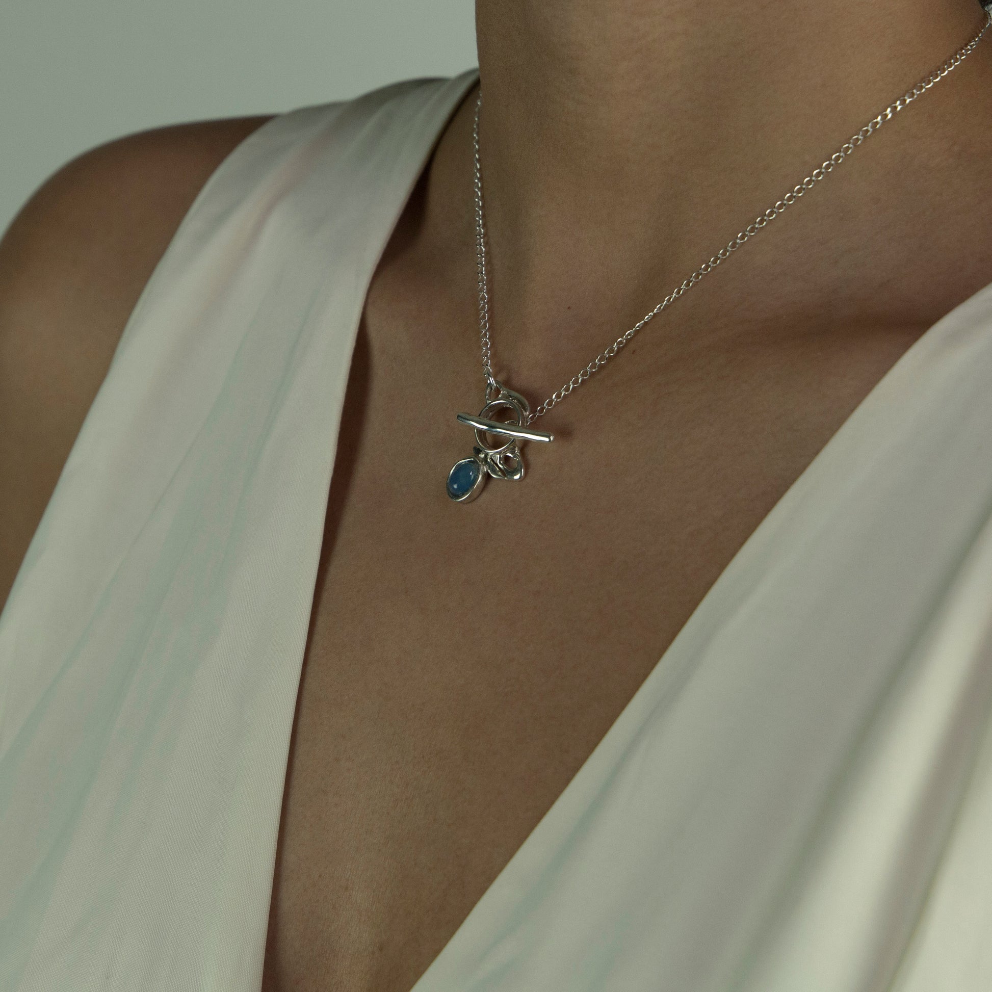 The Felicia necklace is a handmade piece made of 925 sterling silver. Its stone is a semiprecious gem called blue agate. The clasp is located on the front side and is smooth and glossy
