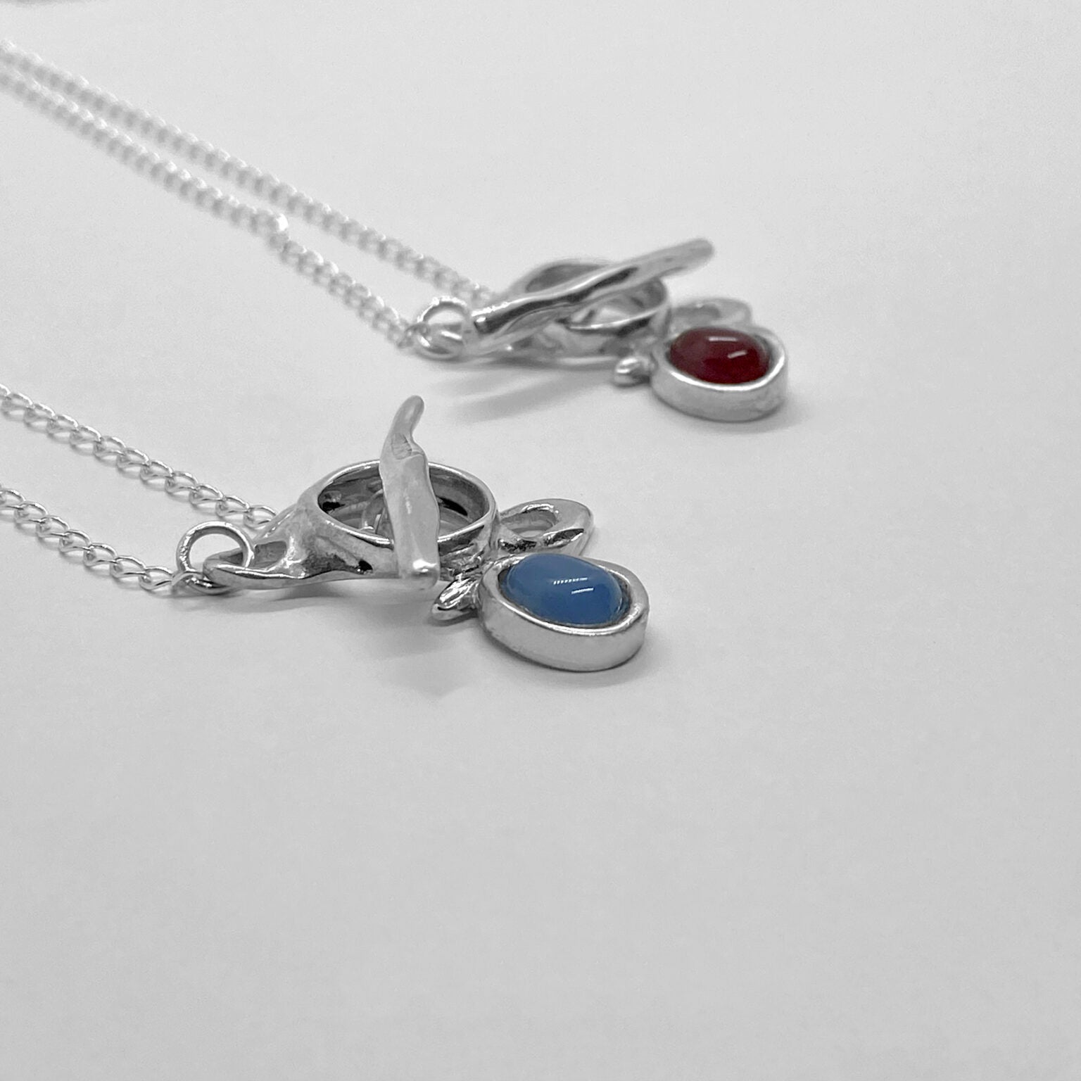 The Felicia necklace is a handmade piece made of 925 sterling silver. Its stone is semiprecious and comes in two colors: red carnelian and blue agate. The clasp is located on the front side and is smooth and glossy. In the photograph, the length of the chain is 40 cm.