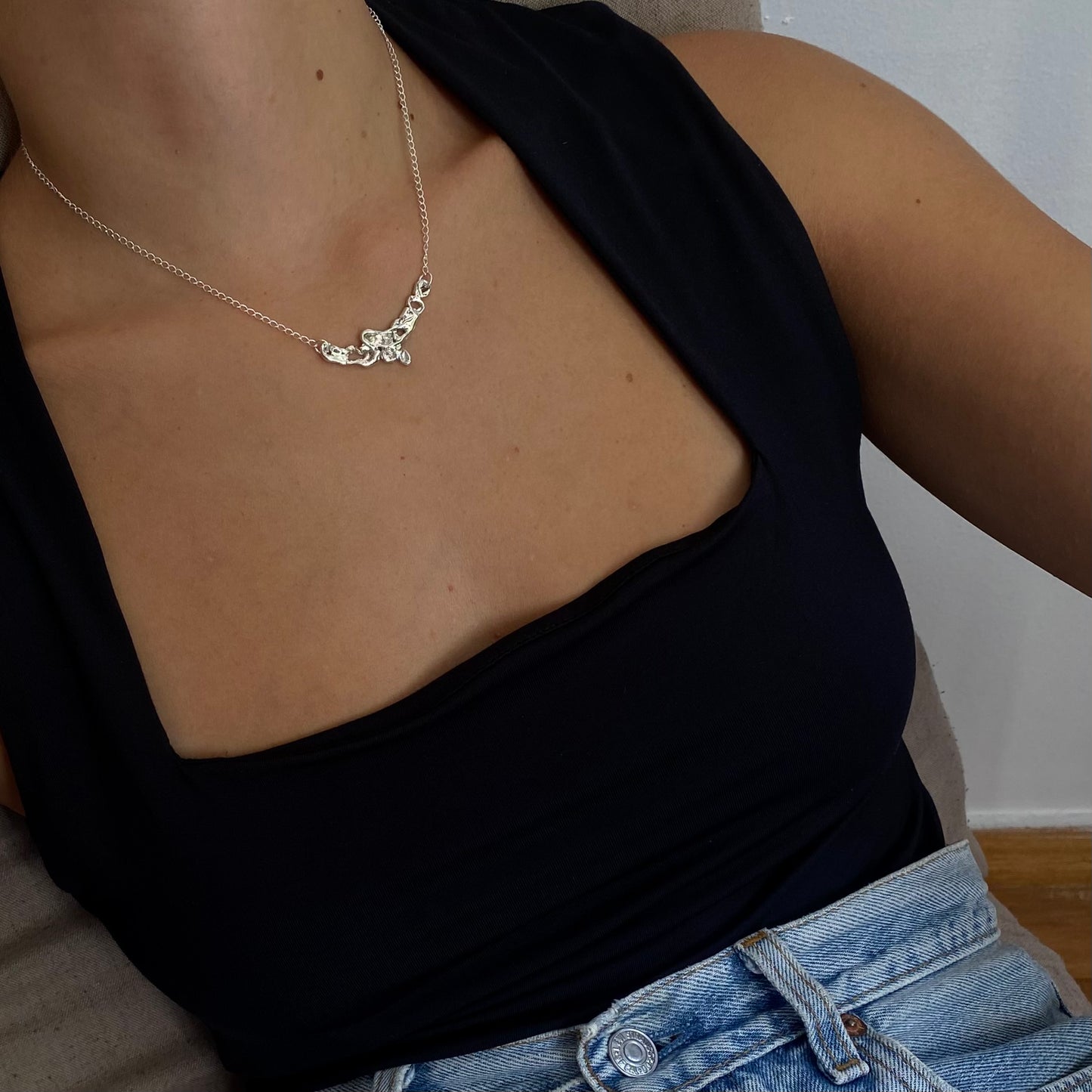 The Camelie necklace is a handmade piece crafted from sterling silver 925. Its design is minimalistic with a raw and glossy appearance, featuring various openings in its interior. Accompanied by a delicate silver chain, the length in the photo is 42 centimeters, and you have the option to choose your preferred length.