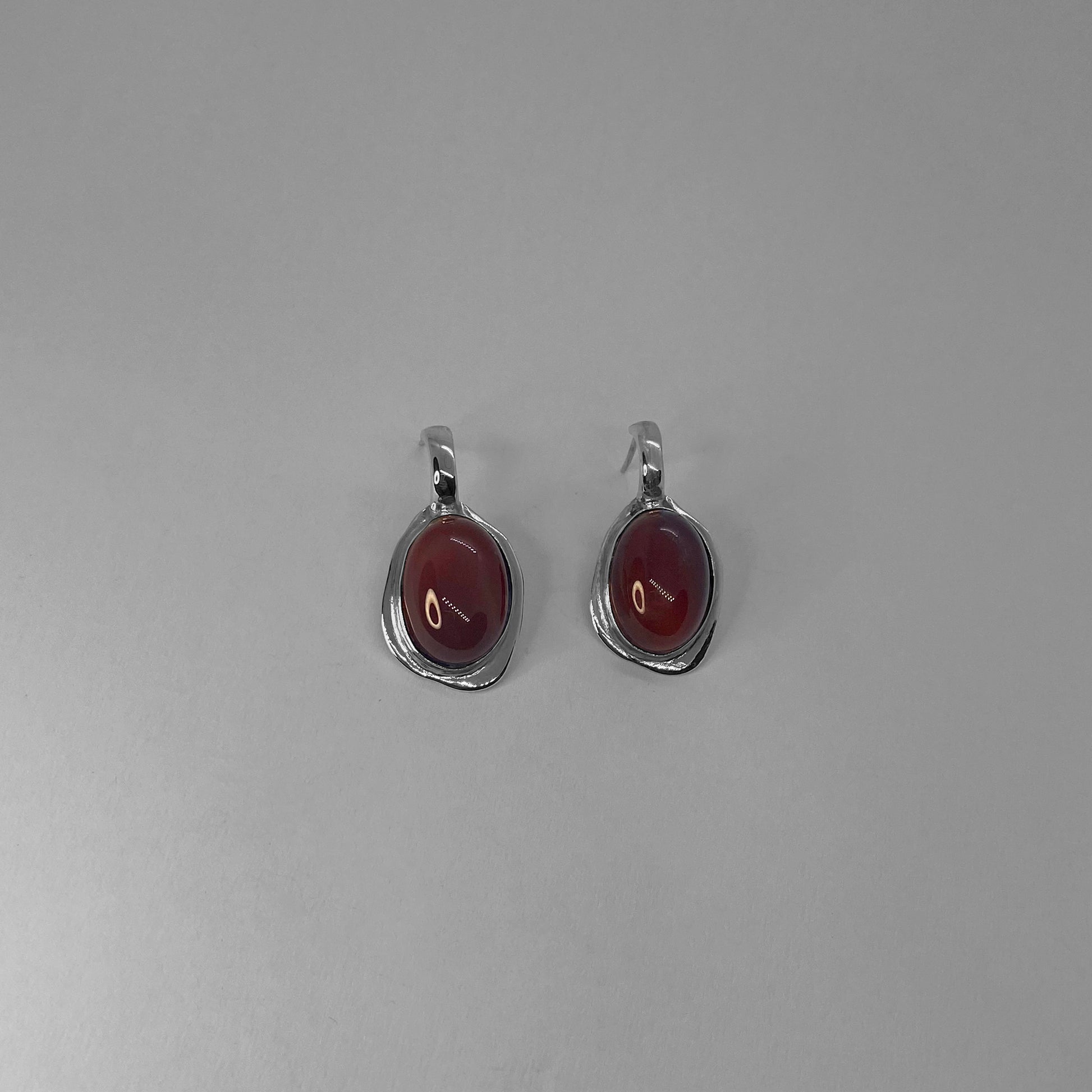 Galene earrings are handmade and made of 925 silver. They are smooth and shiny. The stone featured in the earrings is a semi-precious gemstone. There are two color options: red (carnelian) and black (agate).