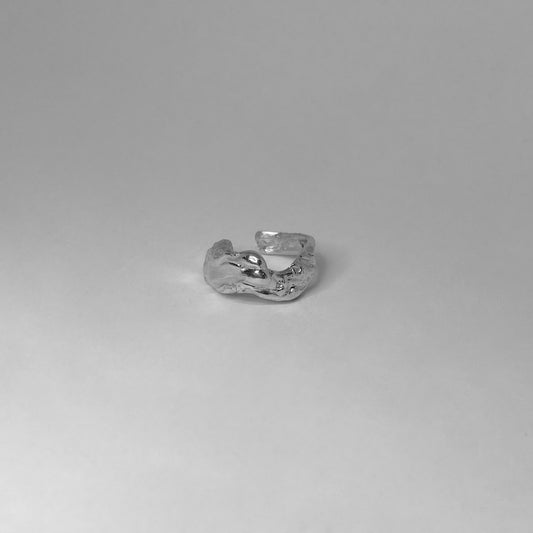 The Lilac ring is handmade and crafted from sterling silver 925. Its design is wavy with a raw texture and form, and it is polished for a smooth finish. The ring is open at the back and can be adjusted to cover up to 3 sizes