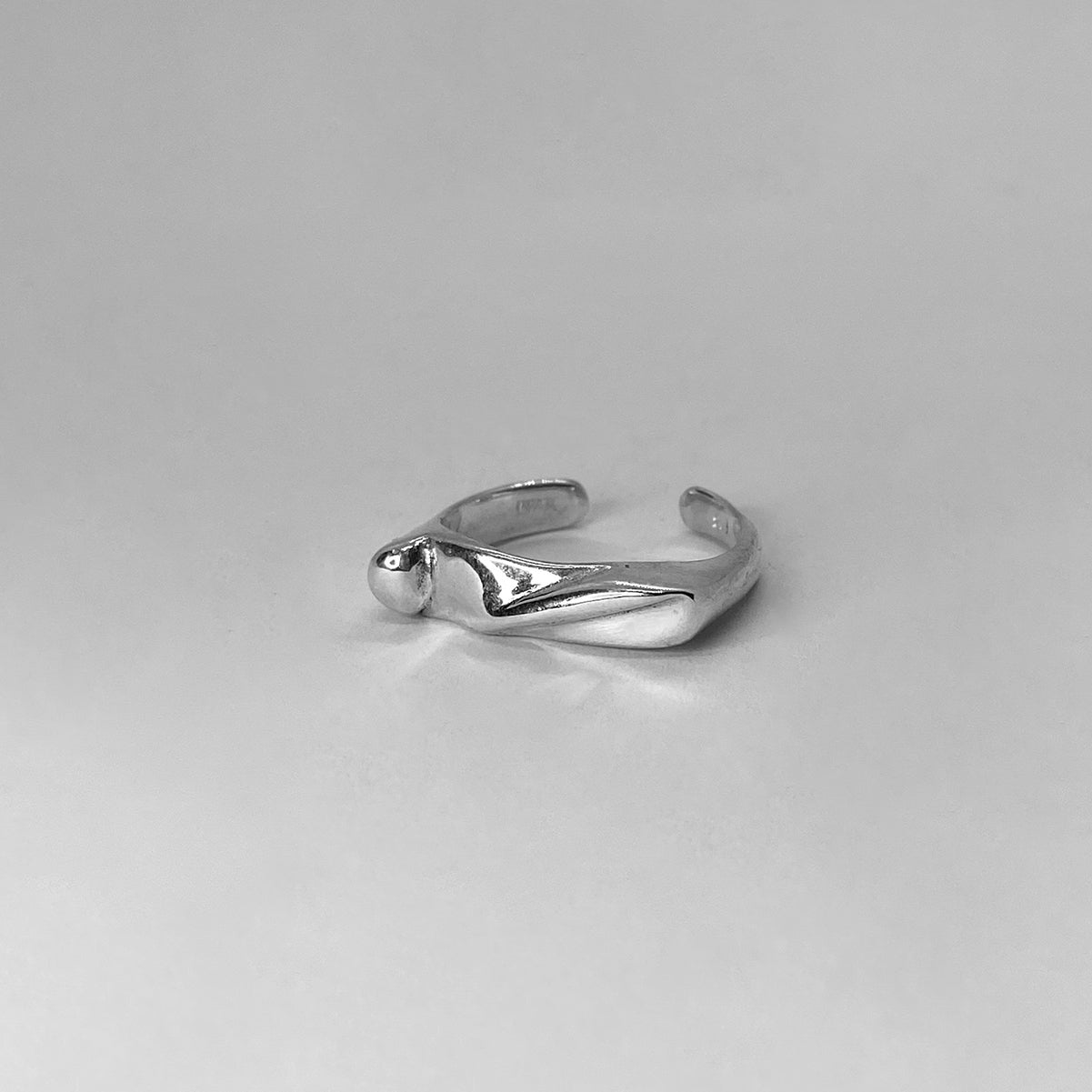 The Shai ring is a handmade piece crafted from 925 sterling silver. It is delicate and has a square shape with different lines on its surface. It has a shiny finish